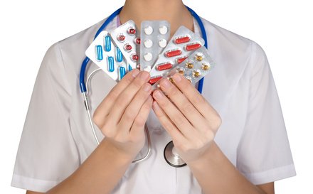 Female doctor with pill holding hand, isolated on white background.